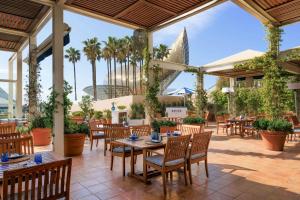 a patio with tables and chairs and palm trees at Hotel Arts Barcelona in Barcelona