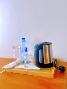 a tea kettle and glasses on a wooden table at JG Luxury Hotel in Dodoma