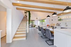 a dining room and kitchen with a staircase and a dining table at VILLA STONE PEARL SUTIVAN - exceptional luxury new three-room villa - private pool and jacuzzi - perfect location right next to the town center and the beach - secured parking space in Sutivan