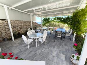a patio with tables and chairs and a stone wall at Apartments Villa Katarina in Tučepi