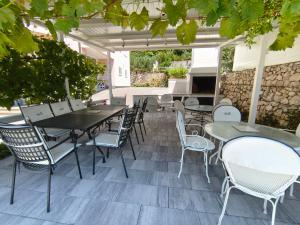 an outdoor patio with tables and chairs and a grill at Apartments Villa Katarina in Tučepi