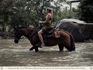 a woman riding a horse through a river at Kantawa Refugio de Bienestar in El Zaino