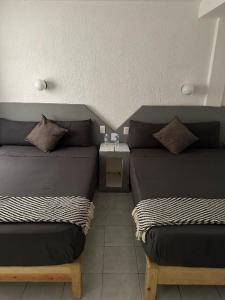 a room with two beds and a table at Hotel Posada Jardín Aguascalientes in Aguascalientes
