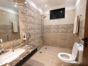 a bathroom with a toilet and a tub and a tv at Opal Orchid House in Islamabad