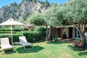 a yard with two chairs and an umbrella at Corfu Glyfada Beach Apartment 13 in Glyfada