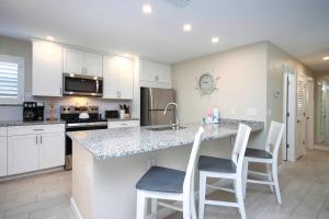 a kitchen with white cabinets and a counter with stools at Sanibel Arms West Unit A1 in Sanibel