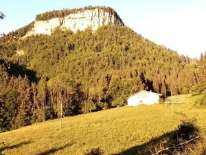 a white barn on a hill in front of a mountain at Le Flocon in Prémanon +2 photos