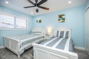 two beds in a bedroom with blue walls and a ceiling fan at Unit D2 in Sanibel +19 photos