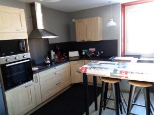 a kitchen with wooden cabinets and a table with stools at Le Flocon in Prémanon