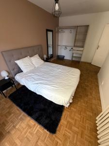 a bedroom with a bed with white sheets and a rug at LebonCosy in Limoges