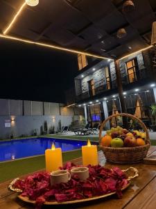 a table with two candles and a basket of fruit at Ohio villa in Sowayma