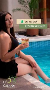 a woman in a black dress sitting next to a swimming pool at El Zapote Casa de Descanso in Malinalco