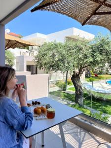 a woman sitting at a table eating food at Thassos OLIVIA RESORT in Potos