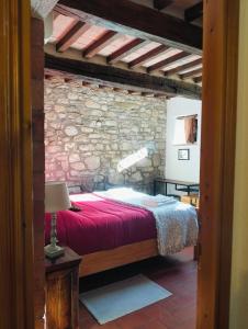 a bedroom with a red bed in a stone wall at Tudesia Charming house in Todi