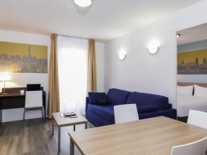 a living room with a blue couch and a table at Aparthotel Adagio Access Paris Clamart in Clamart +55 photos
