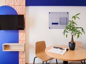 a table with a plant and a tv on a wall at Aparthotel Adagio Access Rennes Centre in Rennes