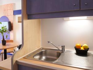 a kitchen sink with a basket of fruit in it at Aparthotel Adagio Access Rennes Centre in Rennes