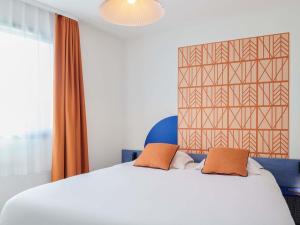 a bedroom with a large white bed with orange curtains at Aparthotel Adagio Access Rennes Centre in Rennes