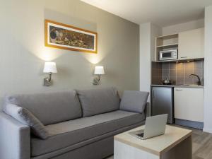 a living room with a couch and a laptop on a table at Aparthotel Adagio Access Avignon in Avignon