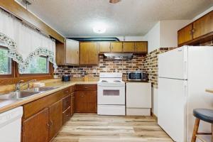 a kitchen with wooden cabinets and a white refrigerator at Hollow's End in Whittier +17 photos
