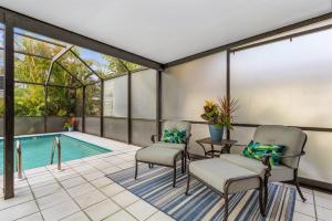 a screened in porch with chairs and a swimming pool at Naples Luxury 5BDRM HomeHtd PoolSuperCleanPets in Naples