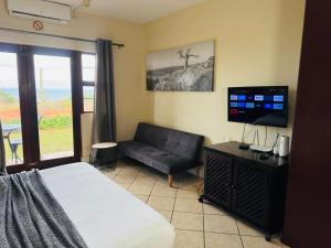 a bedroom with a bed and a couch and a television at Ocean View Villas F05 in Port Edward
