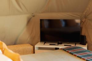 a flat screen tv in a tent with a couch at Manteiros Glamping in Canas de Senhorim