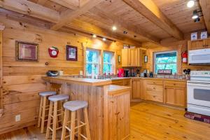 a log cabin kitchen with a counter and stools at Wunderland Cabin in Lake Lure +38 photos