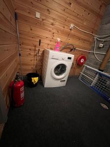 a washing machine in a room with a wooden wall at Basement apartment on Ulstein in Ulstein