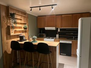 a kitchen with wooden cabinets and a island with bar stools at Basement apartment on Ulstein in Ulstein