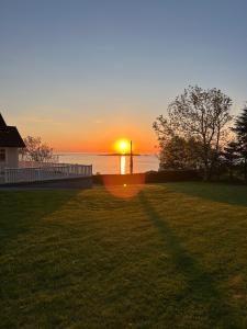 a sunset over the water with a house and a yard at Basement apartment on Ulstein in Ulstein