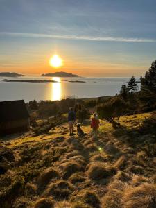 three people standing on a hill watching the sunset at Basement apartment on Ulstein in Ulstein +17 photos