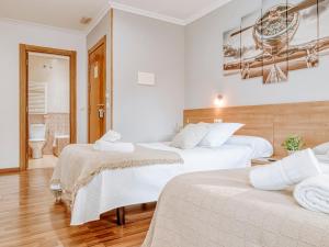 a hotel room with two beds and a bathroom at Aida's Hostal in Puentes de García Rodríguez