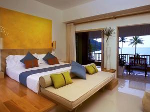 a bedroom with a large bed and a couch with pillows at Mercure Koh Chang Hideaway in Ko Chang