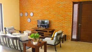 a living room with chairs and a tv and a brick wall at Casa Bul-Kay's - Where Confort Meets Consierge Care in Chicxulub