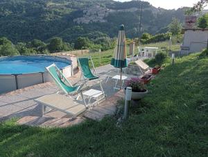 two lawn chairs and an umbrella next to a pool at ai Confini in Castelnuovo di Val di Cecina