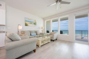 a living room with a couch and a table and windows at Sea Glass 305 in Gulf Shores