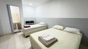 a bedroom with two beds and a bathroom with a sink at Villa Marçal in São Mateus