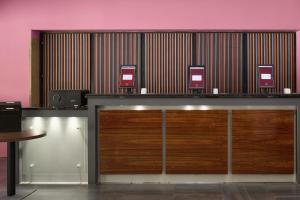 a reception desk with wooden doors and a pink wall at Neuchâtel City Hôtel - Self Check-In in Neuchâtel