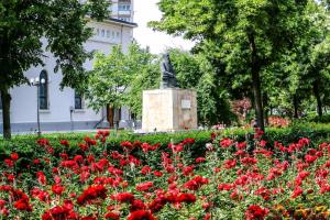 a garden of red flowers in front of a statue at Urban Central Hub in Giurgiu