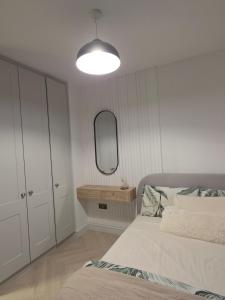 a white bedroom with a bed and a mirror at The Boulevard in Dublin