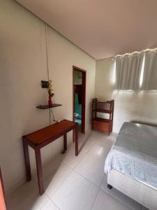 a bedroom with a bed and a table and a chair at Hostel e Suites Caminho do Vale in Palmeiras