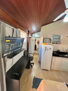 a room with a kitchen with a refrigerator and a tv at Pousada Moradia da Fabi in Bragança Paulista