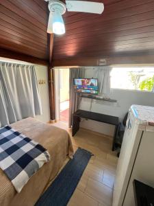 a bedroom with a bed and a desk with a television at Pousada Moradia da Fabi in Bragança Paulista