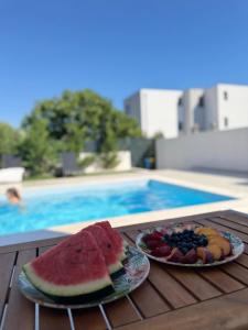 two plates of fruit on a table next to a swimming pool at Luxury Villa Rubi Vir - private pool in Vir