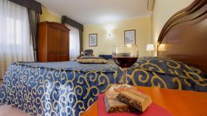 a glass of wine sitting on a table next to a bed at Hotel Villa Ada in Pozzallo