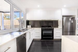 a kitchen with white cabinets and a stainless steel refrigerator at SeaBreeze On Todd in Yeppoon