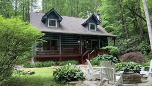 a house with a porch and chairs in the yard at Hickory Creek Hideaway in Maggie Valley