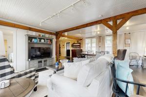 a living room with white furniture and a television at Sassafras Cottage in Waynesville