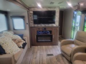 an rv living room with a tv and a couch and a fireplace at Cozy Camper in Newfield